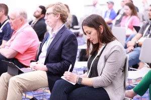 3 WasteExpo attendees taking notes while sitting in on a conference session
