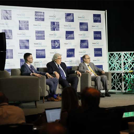 Panel of 3 presenters sitting onstage in chairs at the investors summit