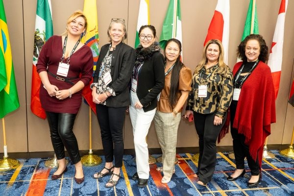 6 attendees posing in front of flags at the international reception