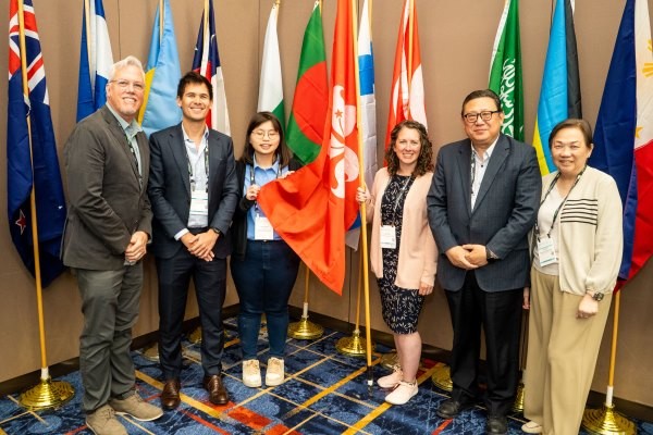 6 attendees posing in front of flags at the international reception