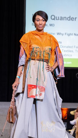 Women wearing a dress made of trash walking the runway at Trashion